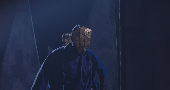 Mystic footage of metal masked man . Epic scene of people with triangle shape mask and black costume cloak . Unfaced men watching or following something or someone . Anonymity or Anonym follower theme