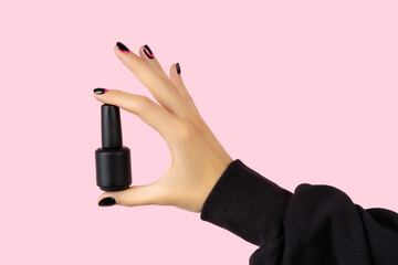 Womans hand with trendy manicure holding nail varnish on pink background - obrazy, fototapety, plakaty