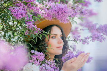 Portrait of a beautiful young woman in a blooming lilac park. Purple flowers. Spring. Happiness.