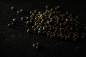 Close up of a complete group of dried peppercorns slightly offset on the top right of a slate plate