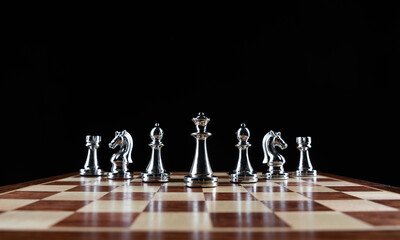 Silvery chess figures standing on chessboard