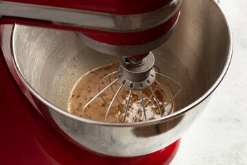 whipping eggs with sugar in the bowl of the mixer, the woman adds sugar