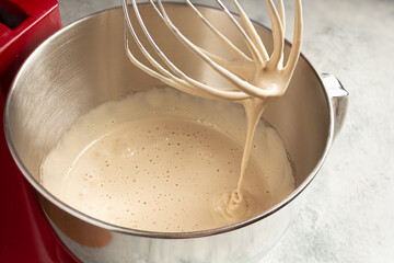 Fototapeta premium whipping eggs with sugar in the bowl of the mixer, the woman adds sugar