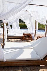 Wooden beach canopies covered by fabric on the beach of the Mediterranean Sea. White curtain being...