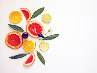 Natural cosmetics with vitamin C, a bottle with a cosmetic product with citrus essential oil on the background of plastics of lemons, oranges, grapefruit. Copy space. Citrus skin whitening concept