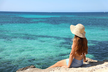 Longing for summer, longing for holidays. Back view on female tourist enjoying view crystalline water of the ocean.