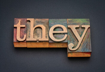 they - word abstract in vintage letterpress wood type against black matte background