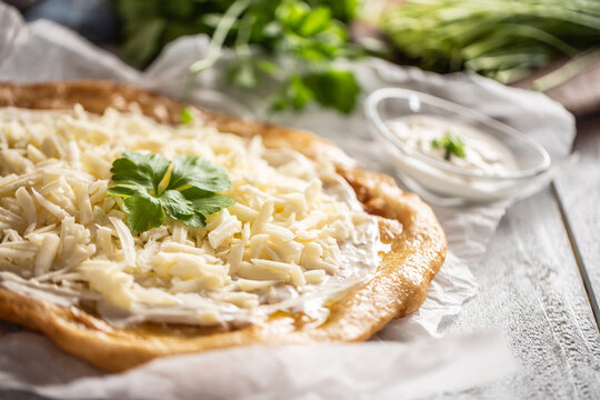 Closeup of a hungarian baked langos served with loevly cream, cheese, garlic and fresh green onion