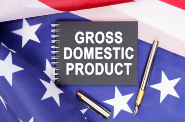 Fototapeta na wymiar On the table is an American flag, a pen and a notebook with the inscription - GROSS DOMESTIC PRODUCT