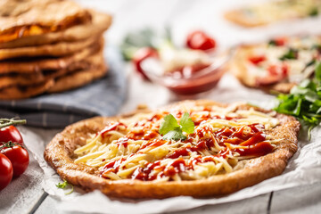 Original hungarian langos with grated cheese and ketchup served o a table with other lovely and tasty doughs and vegetables