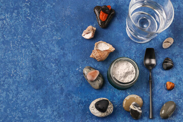 Fototapeta na wymiar Healthy lifestyle concept. Hydrolyzed marine collagen powder in a glass jar and a glass of clean water among the stones on a blue background. Natural supplement. Copy space.
