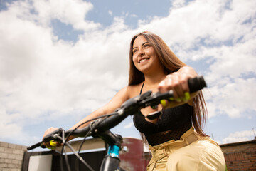 Smiling latin girl riding her bicycle. Modern youth lifestyle and eco-friendly mobility concept.