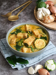 A bowl of Thai red curry with pork belly with water spinach or Gaeng Tay Po in Thai. With its ingredients and herb to make curry paste. It's a sweet and aroma taste from coconut and kaffir lime leaves