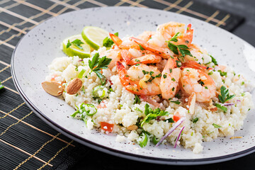 Couscous with roasted shrimps, tomatoes, red onions, almond nuts and parsley. Moroccan food with couscous and prawns.