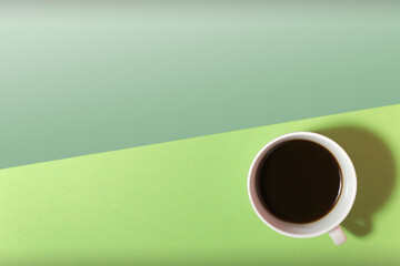cup of coffee on a green and light green background top view