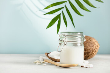 Coconut oil in jar with fresh coconut and tropical leaves, Spa cosmetic and food ingredient, copy space