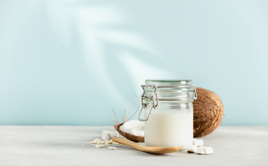 Coconut oil in jar with fresh coconut and tropical leaf shadow, Spa cosmetic and food ingredient