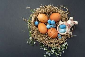 Natural eggs with Easter eggs, feathers in a nest on a dark background. Top view, Happy Easter. Easter Holiday,