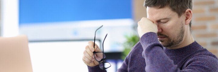 Man siting at table in office and holding bridge of his nose © megaflopp