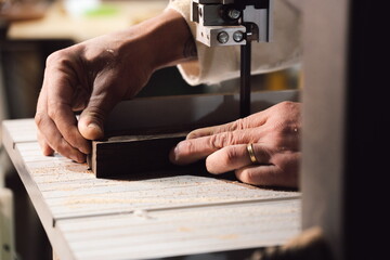 Cabinetmaker hands cutting wood with electric saw