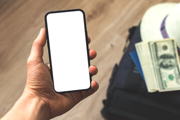 Hand with screen mockup on background of traveler bag, money and straw hat, concept template pf preparation for world triip, copy space photo