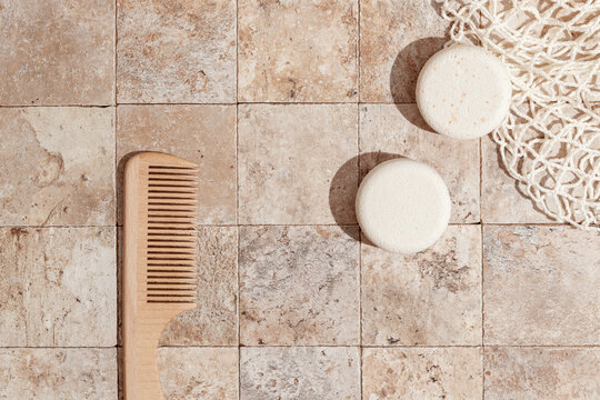 Zero waste care for skin - dry shampoo, wood brush on earth toned stone tales top view direct sunlight