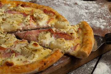 Cutting a slice from a pizza of pork loin with cream cheese and pineapple or lombo ao creme com...