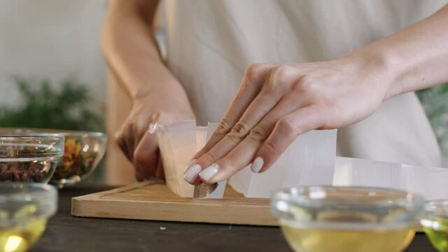 Midsection close up of female hands dicing premade soap base using melt and pour method of making natural diy soap