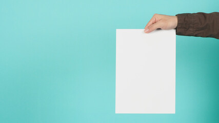 Blank or empty board paper in man's hands on green mint or Tiffany Blue background.man wear navy shirt.