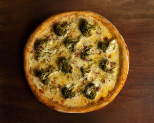 Top view of one whole broccoli pizza on wooden board or table with bacon