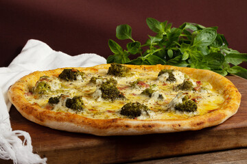 One whole broccoli pizza on wooden board and table with bacon