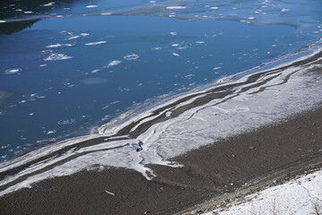 ice sheet covering part of the beach and water  in Serre Ponçon lake, France
