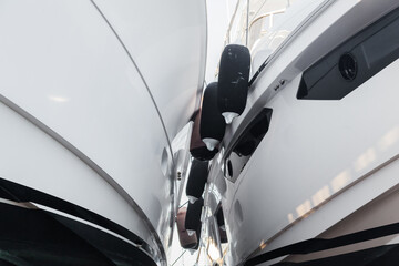 Fototapeta premium Two white luxury yachts stand side by side in dry dock with fenders on the sides.