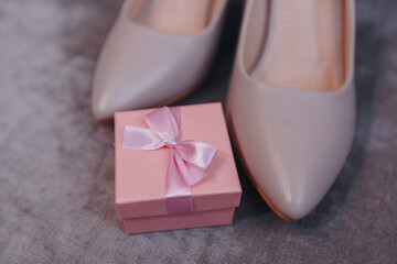 Pink wedding box for rings on the gran facture background. Near standing bridal biege shoes.