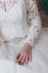 Brides hand laying on the wedding dress with lace closeup