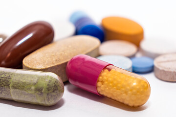 Close-up colorful assorted soft capsules pill vitamin tablet blue pink yellow brown supplements on white background