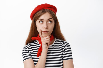 Naklejka premium Close up of thoughtful girl student in french beret thinking of solution, looking aside with pensive face, standing over white background