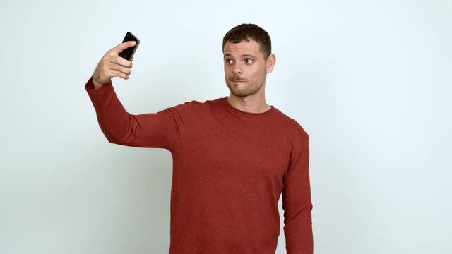 Brazilian handsome man using mobile phone and doing a selfie over isolated background