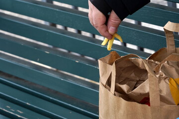 Man eating French frites with fingers from paper bag on a wooden bench in Bern, Switzerland. Take away food becomes street food in time of coronavirus and covid-19 crisis when restaurants are closed.