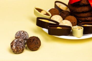 Chocolate truffles and chocolates with nuts on a yellow background.