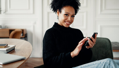 A female student of Brazilian appearance holds a phone in her hands. Writes a letter to a friend in...