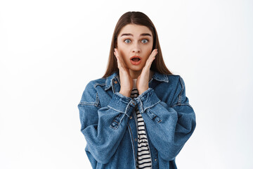 Shocked startled girl cant believe her eyes, drop jaw, gasping and holding hands near face look...