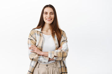 Stylish woman cross arms on chest and smiles, looks confident and assertive, standing like professional, white background