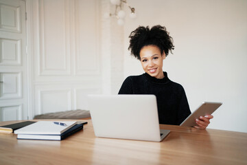 A contented woman of Afro appearance. A woman keeps online accounting of expenses for a month at home. Records costs in a convenient app.