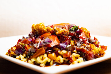 Um prato branco quadrado com yakisoba vegetariano.