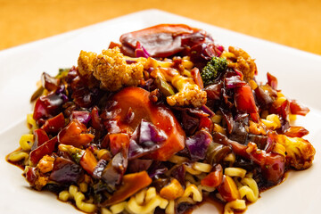 Um prato branco quadrado com yakisoba vegetariano.