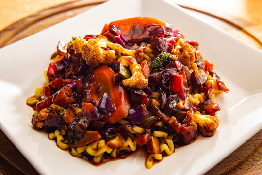 Um prato branco quadrado com yakisoba vegetariano.