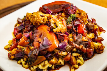 Um prato branco quadrado com yakisoba vegetariano.