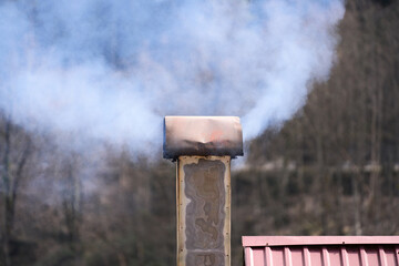 Fototapeta na wymiar White smoke comes out of the metal chimney. Copy space.