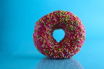 Berliner donut pink chocolate lies stands on a blue bright background with a place to text a copy of the still life for the kitchen breakfast sweet meal